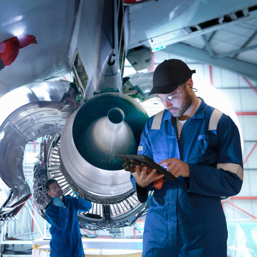 Person working in front of a plane engine.