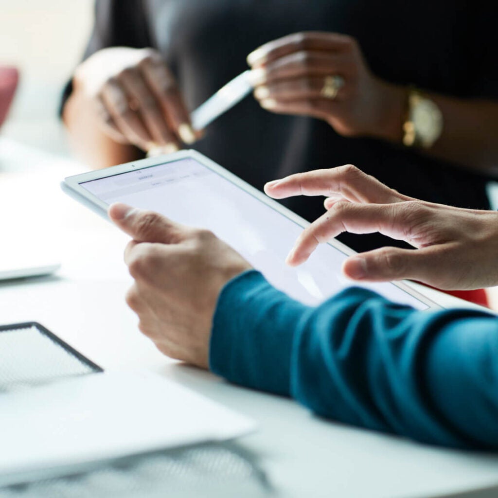 Close-up of people working on a tablet.