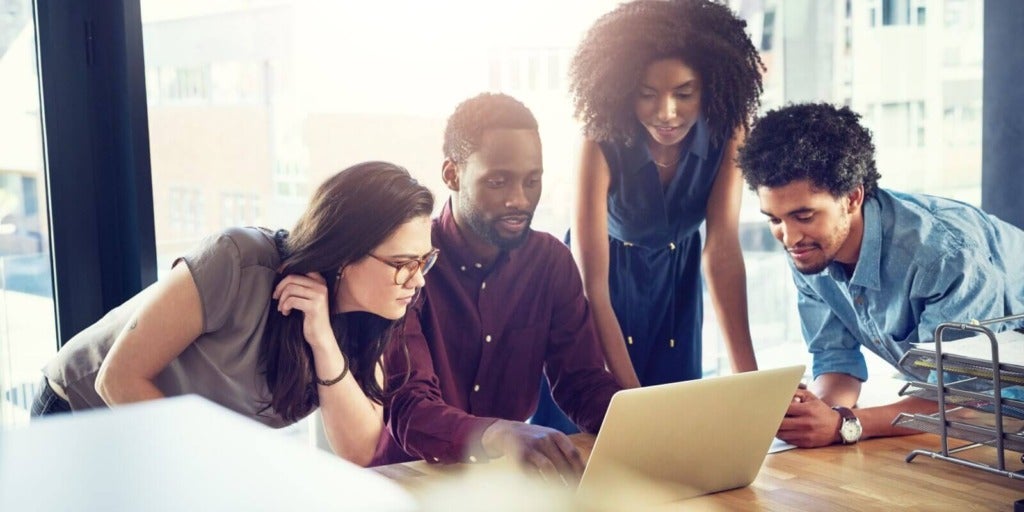 Teammates gathered around a laptop, discussing AI capabilities